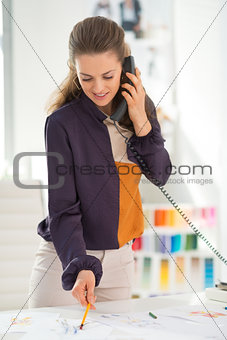 Happy fashion designer in office talking phone