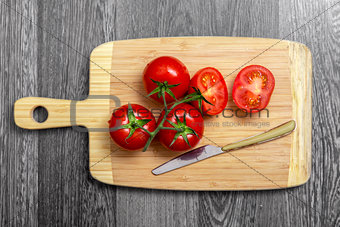 Top view of fresh tomatoes and knife on chopping board 