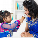 Indian girl feeding her mum ice-cream.
