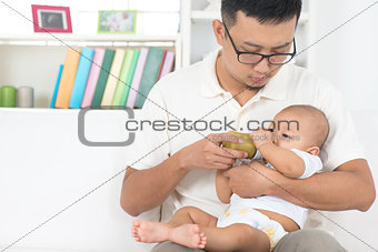Father bottle feeding baby