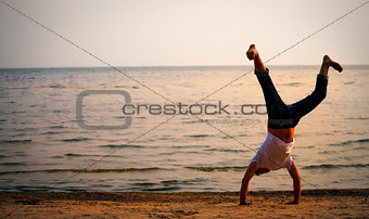 man doing handstand on beach