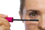 Closeup on young woman applying mascara