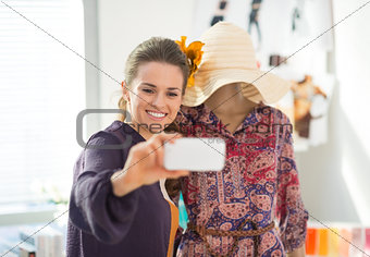 Happy fashion designer taking self photo with garment