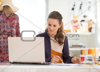 Fashion designer with laptop working in office