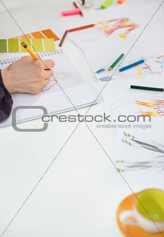 Closeup on fashion designer making sketches in office