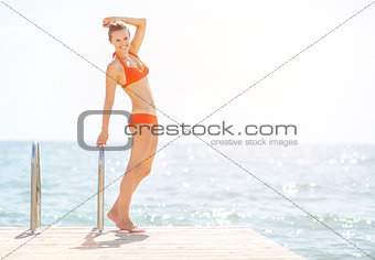 Full length portrait of happy young woman standing on bridge