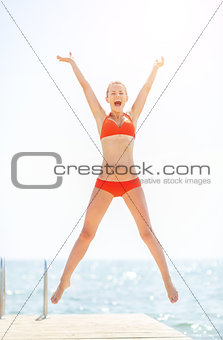 Happy young woman jumping on bridge