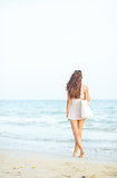 Young woman walking on beach in the evening. rear view