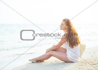 Young woman sitting on beach in the evening