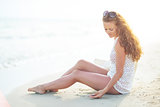 Happy young woman sitting on beach in the evening