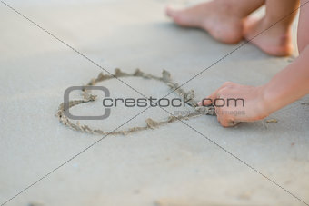 Closeup on young woman drawing on sand