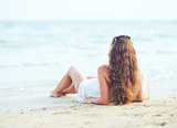 Young woman relaxing on beach in the evening. rear view