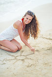 Young woman on beach drawing on sand