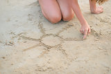Closeup on young woman drawing on sand