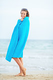 Full length portrait of young woman standing on beach in towel