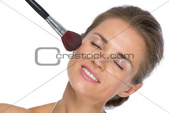 Young woman using makeup brush