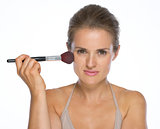 Portrait of young woman using makeup brush