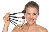 Portrait of happy young woman with makeup brushes
