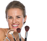 Portrait of smiling young woman with makeup brushes
