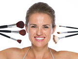 Portrait of smiling young woman with makeup brushes