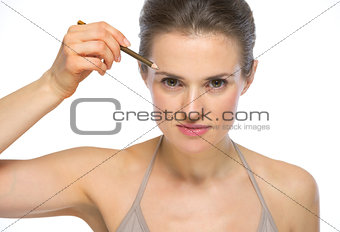 Portrait of young woman using eyebrows pencil