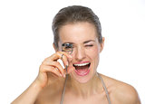 Portrait of happy young woman using eyelash curler
