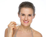 Portrait of smiling young woman with tweezers