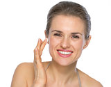 Portrait of happy young woman applying creme on face