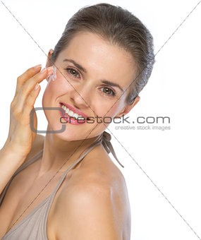 Portrait of happy young woman applying creme