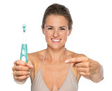 Portrait of smiling young woman pointing on toothbrushâ