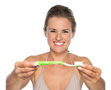 Portrait of happy young woman showing toothbrushâ