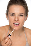 Portrait of happy young woman applying lip gloss