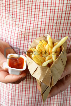 paper bag with potatoes french fries and ketchup in the hands