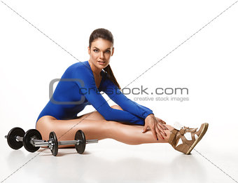 Woman bodybuilder posing after a workout near dumbbells.