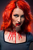 Portrait of a redhead woman with blood in her lips and neck 