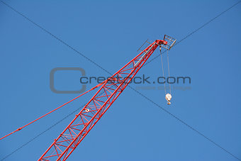 Red crane boom against a blue sky