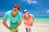Portrait of happy young couple in bright clothes and sunglasses having fun on tropical beach