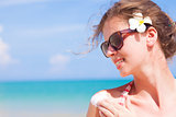 Young woman in sunglasses putting sun cream on shoulder