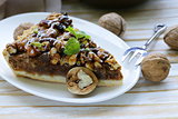 piece of pecan pie tart with various nuts on a wooden board