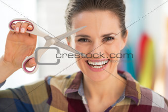 Portrait of smiling seamstress showing scissors