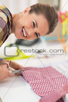Happy seamstress cutting fabric