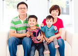 happy asian  family sitting on a white leather sofa 