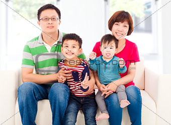 happy asian  family sitting on a white leather sofa 