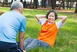 smiling senior grandmother doing sit-ups in the park