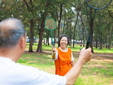 senior couple or friends playing badminton in the park