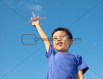 happy boy holding a airplane toy with blue sky