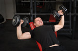 Young man doing Dumbbell Incline Bench Press workout in gym