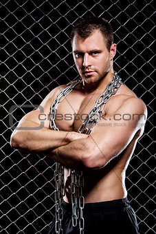 Powerful guy with a chain showing his muscles