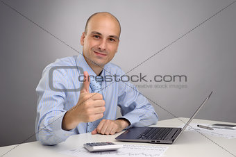 business man working on laptop and making the ok gesture