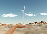 Hand holding wind turbine against a desert